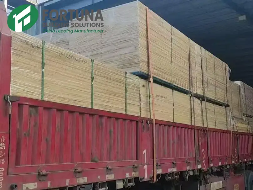 Large bundles of wholesale MDF board being loaded and strapped onto a red flatbed delivery truck for bulk shipping from a professional MDF manufacturer.