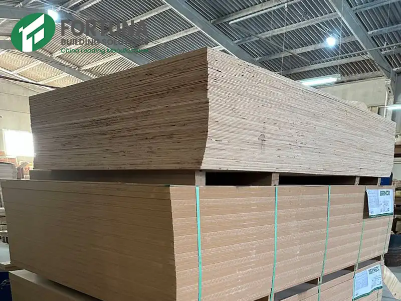 Large pallets of raw wholesale MDF board stacked neatly inside a manufacturing factory warehouse, ready for shipping by a leading MDF manufacturer.